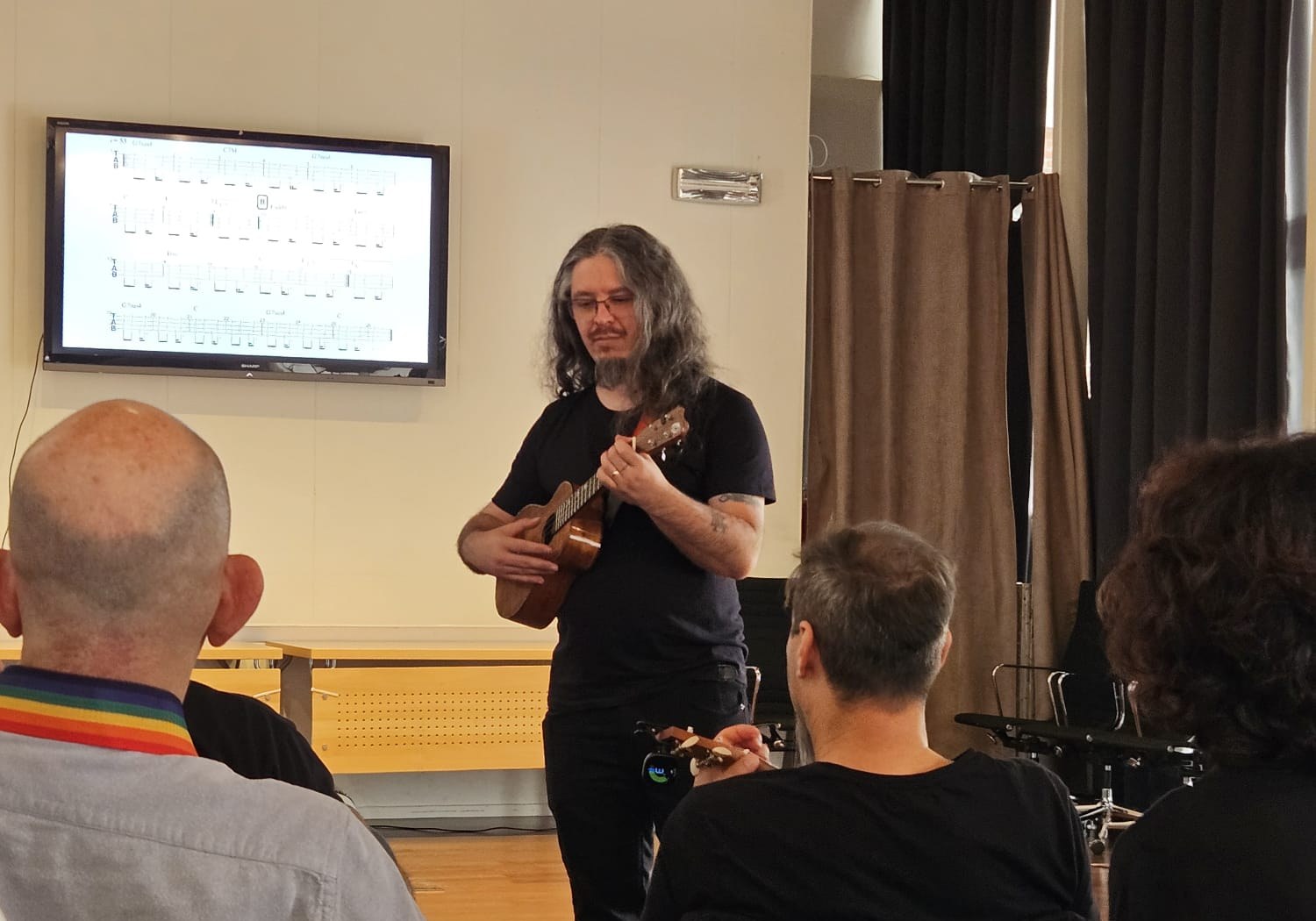 João Tostes ensinando ukulele em oficina prática